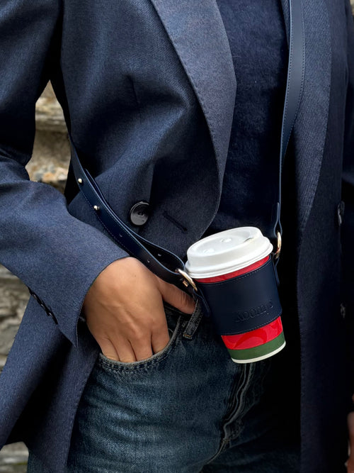Boisson a emporter maintenue par un porte gobelet koomys porté en bandouliere. Il permet de se balader avec son cafe en gardant les mains libres
