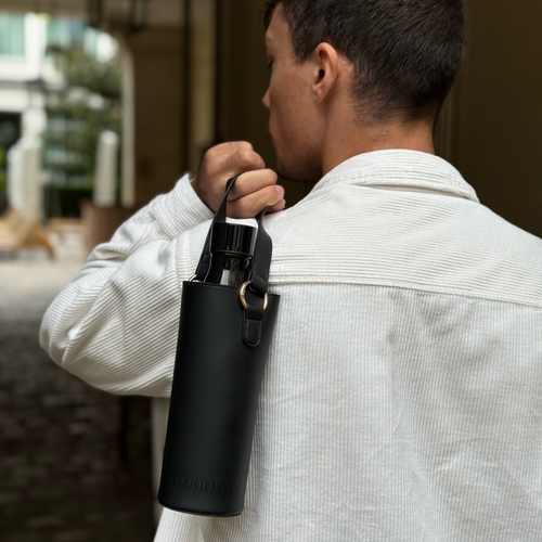 Porte-gourde en cuir vegan noir KOOMYS porté à l’épaule pour transporter une bouteille